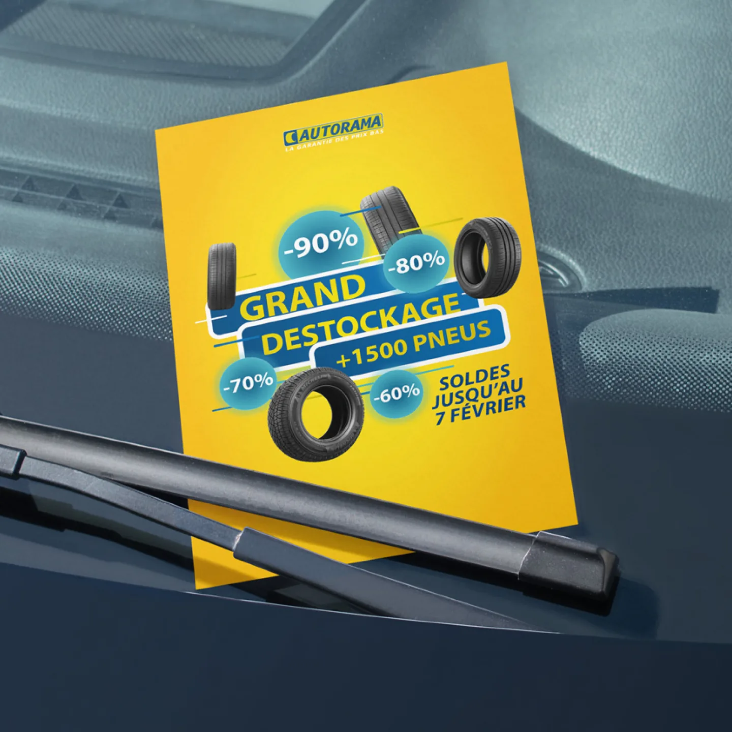 Flyer Autorama « Grand déstockage, plus de 1 500 pneus » glissé sous un essuie-glace