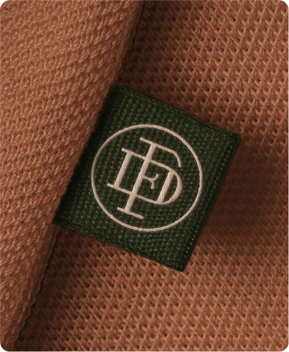 Étiquette au sigle DF de Dormez Français sur un tissu texturé terracotta