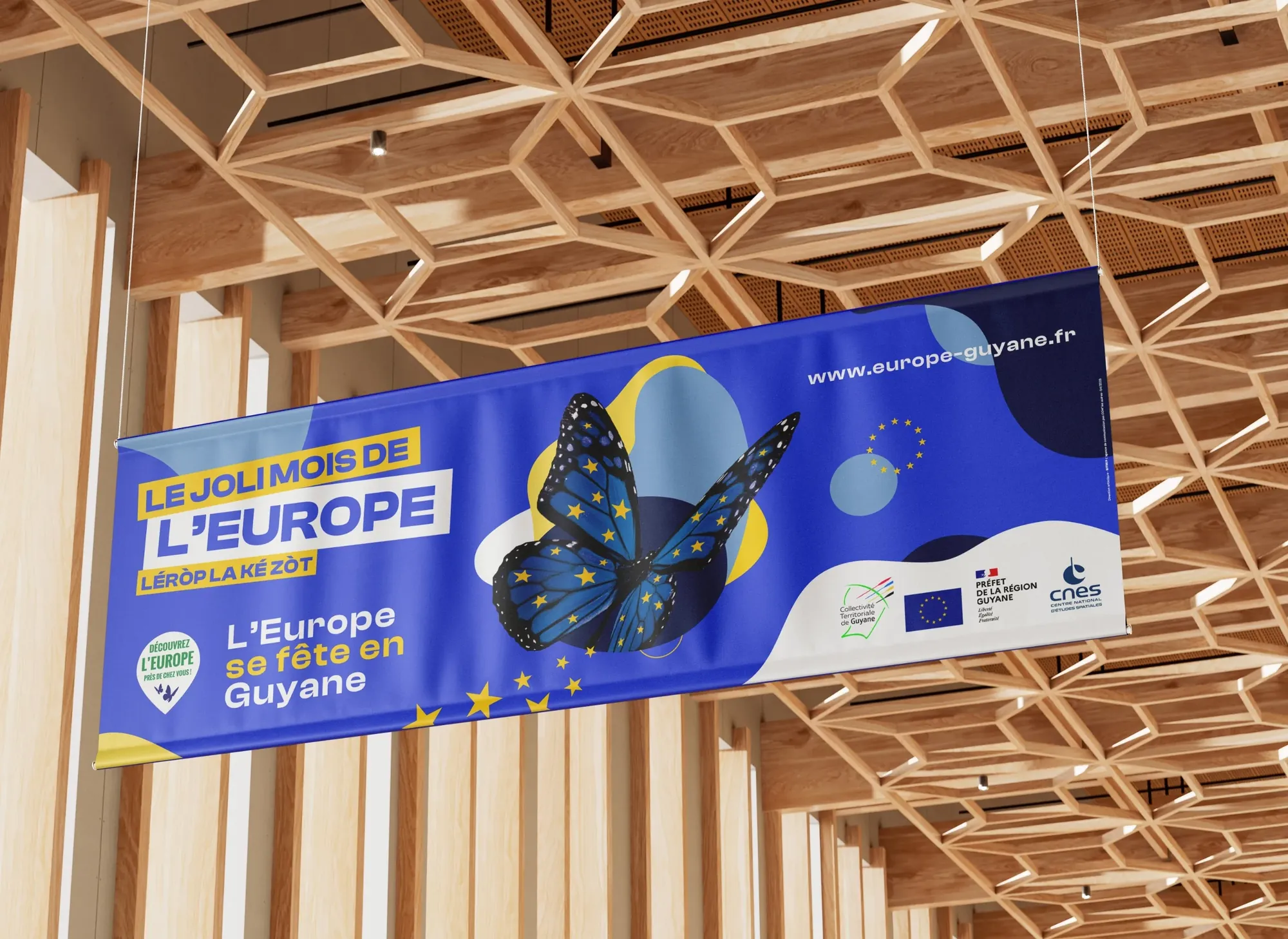 Univers graphique Europe en Guyane : bannière du Joli Mois de l’Europe, mise en situation sous une charpente en bois