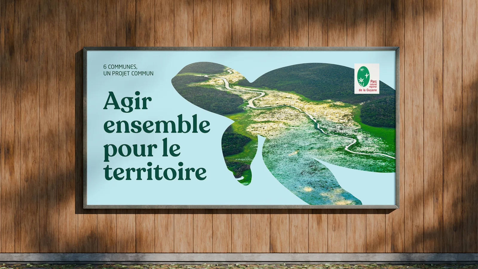 Affiche « Agir ensemble pour le territoire » du Parc naturel régional de la Guyane : une vue aérienne dans la silhouette d’une tortue (mise en situation sur un panneau)