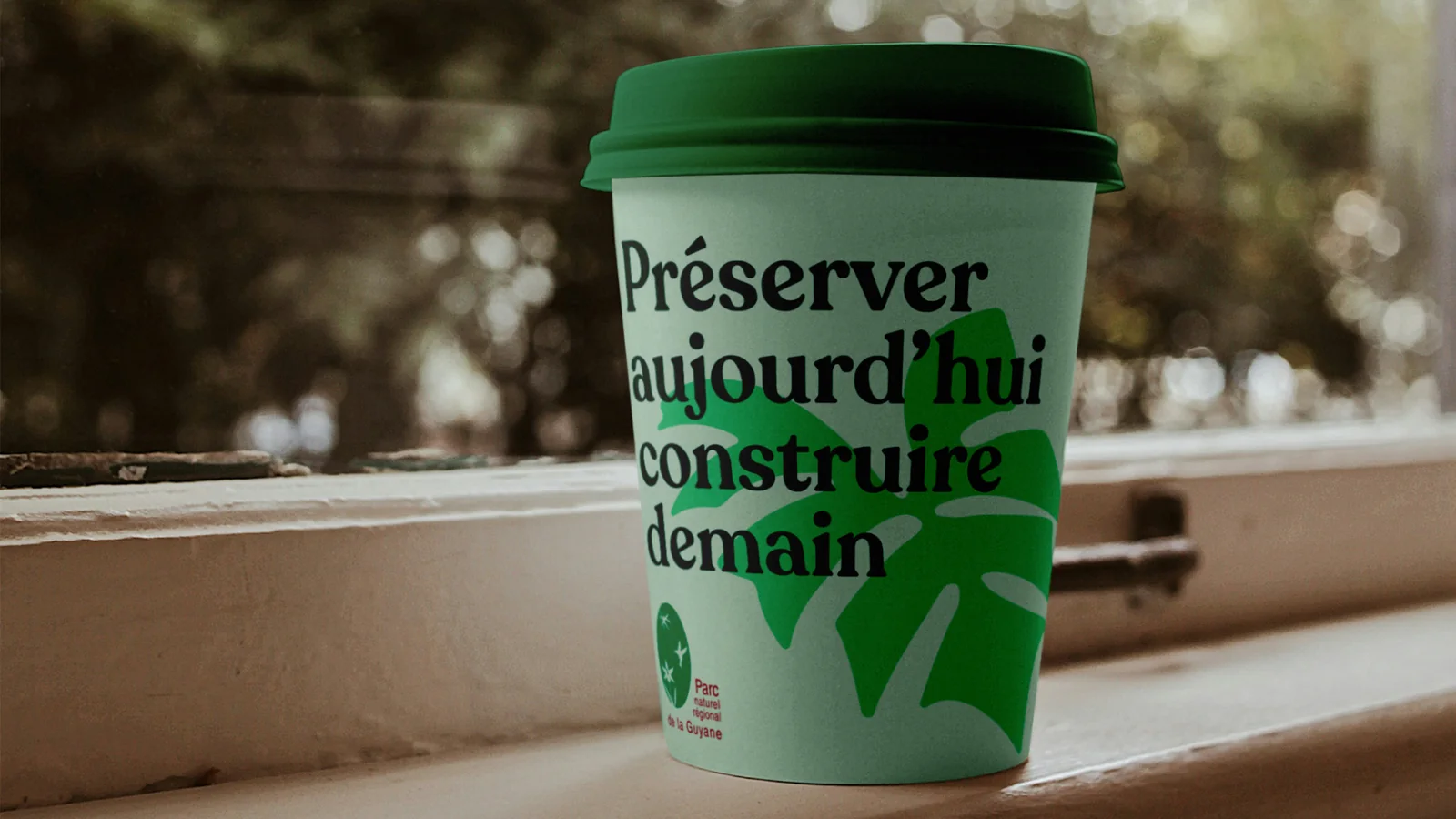 Gobelet « Préserver aujourd’hui construire demain » avec une feuille verte (mise en situation)