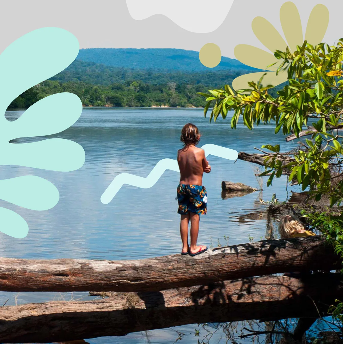 Enfant debout sur un tronc au bord d’un fleuve de l’Ouest guyanais, entouré des formes végétales du guide