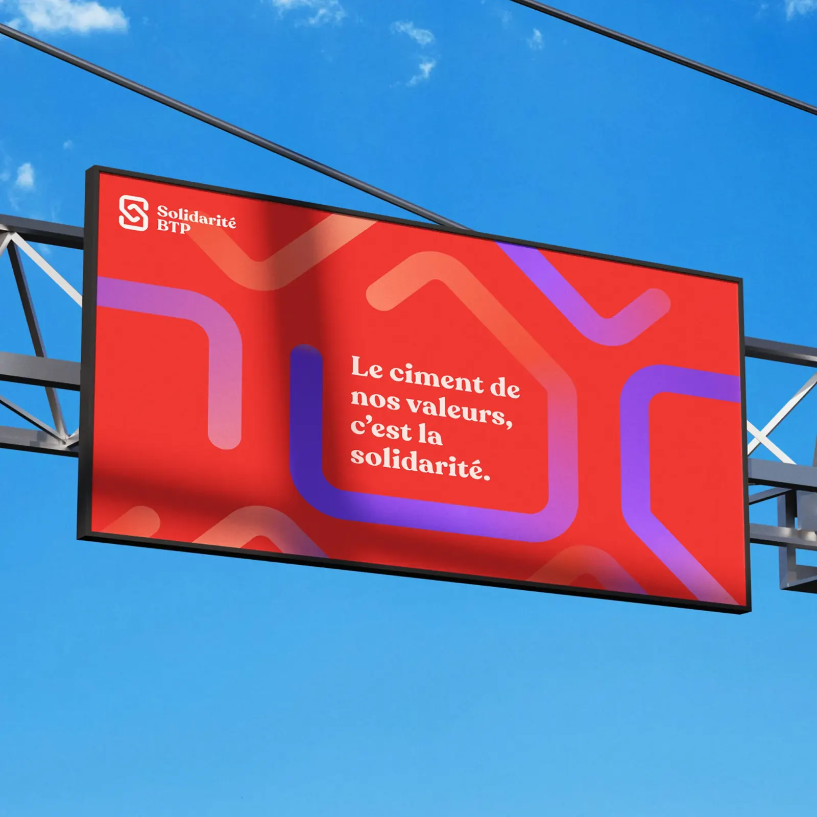 Panneau d’affichage Solidarité BTP sur fond de ciel bleu : « Le ciment de nos valeurs, c’est la solidarité. » (mise en situation)