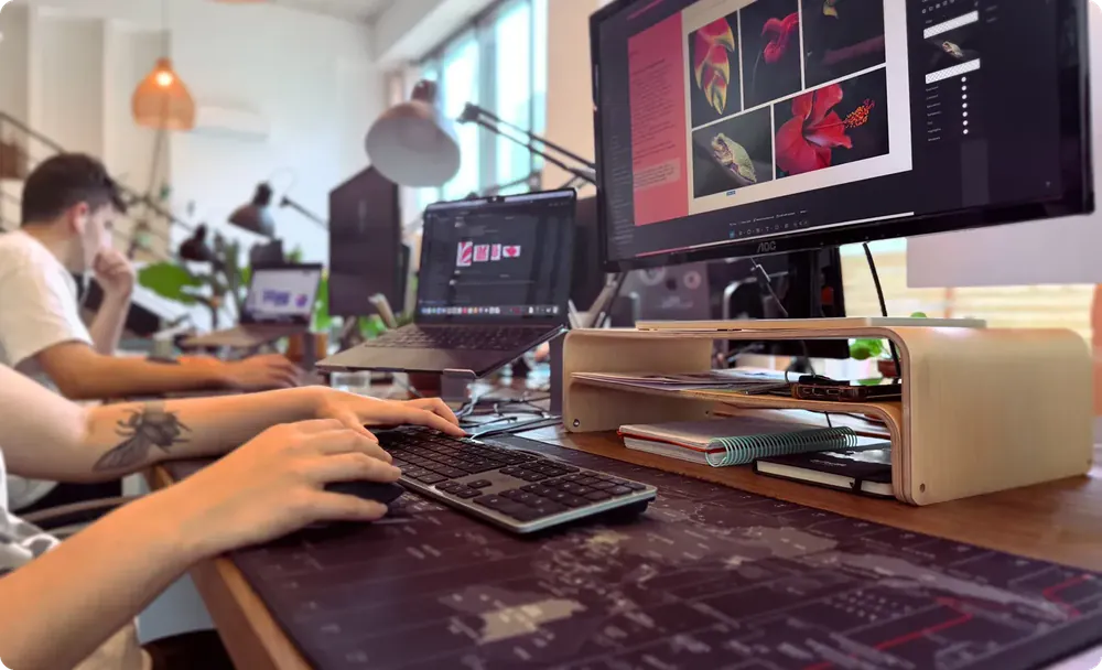 Poste de graphiste à l’agence : mains sur le clavier, écran de retouche photo de fleurs rouges
