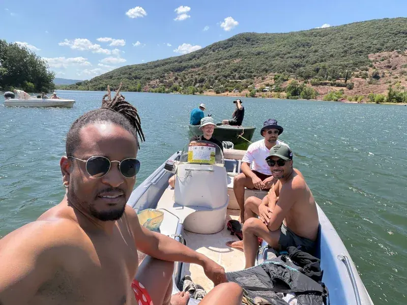 Selfie de l’équipe sur un bateau, collines verdoyantes en arrière-plan