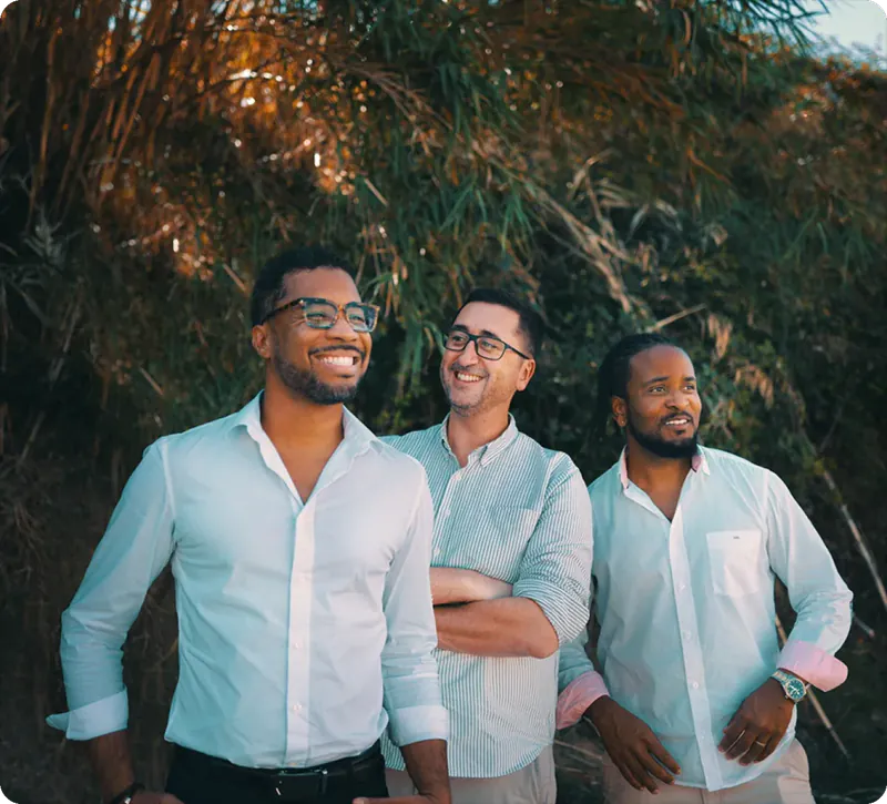 Trois membres de l’équipe Bitwip en chemise claire, sourire aux lèvres, sous des palmiers
